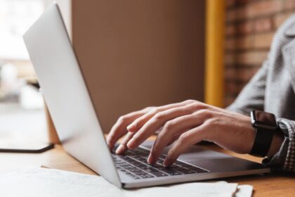 cropped image businessman eyeglasses sitting by table cafe using laptop computer