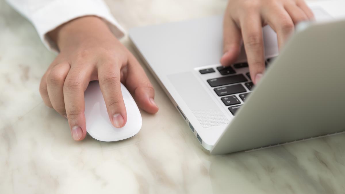 person writing with one hand other touching mouse